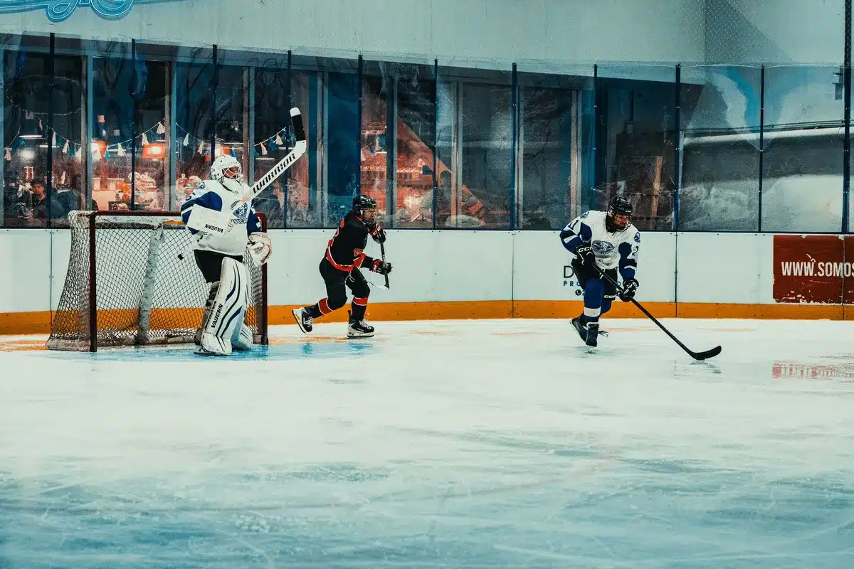 Hockeyspelare firar ett mål på isen med höjd stick under matchbelysning