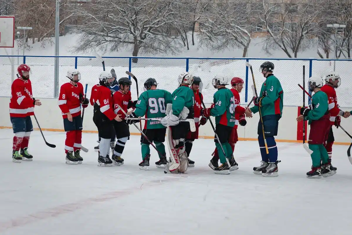 Ishockeyspelare i lagtröja får beröm från lagkamrater på isen under match eller träning