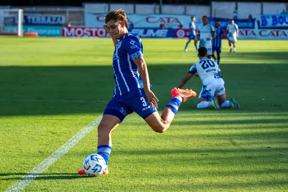 Fotbollsspelare i straffposition med målvakt i bakgrunden på belyst fotbollsplan