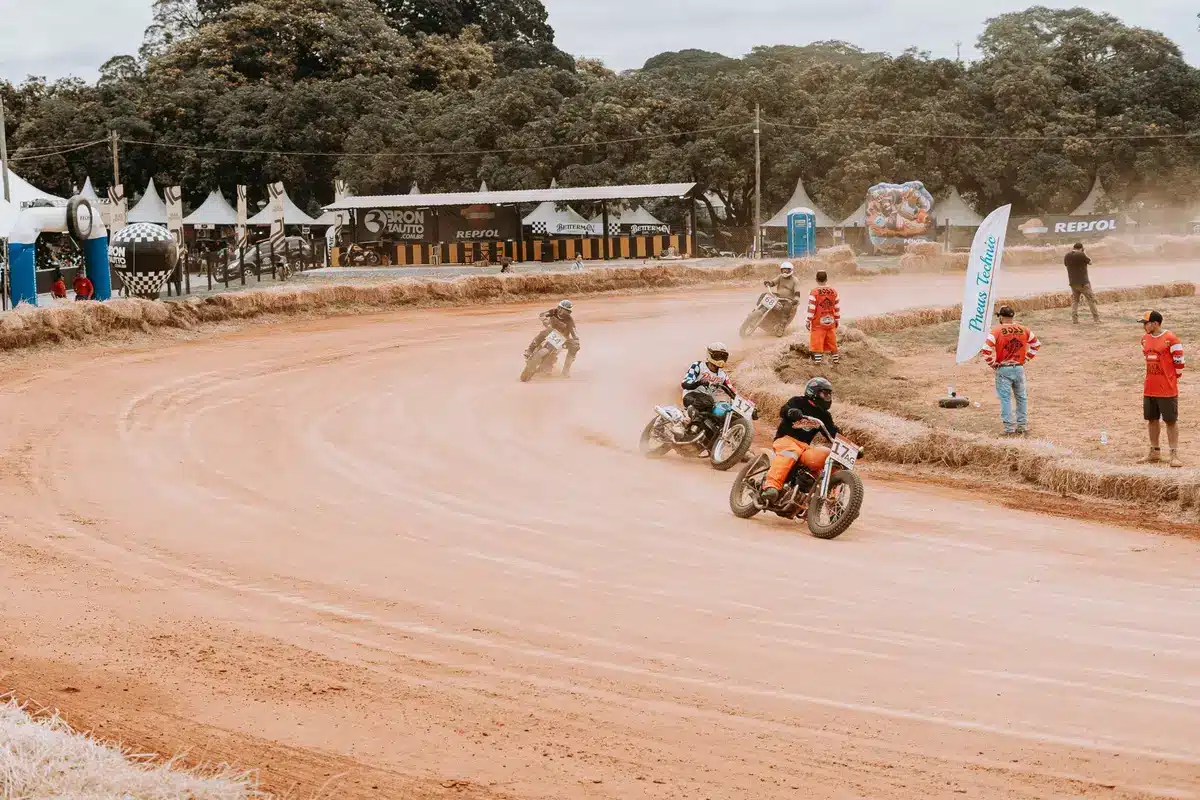 Motorcyklister i höga hastigheter genom regnsläta kurvorna på en Grand Prix-bana