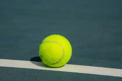 Två tennisspelare i intensiv rally på gräsmatta, en slår en kraftfull forehand medan motståndaren försvarar sig
