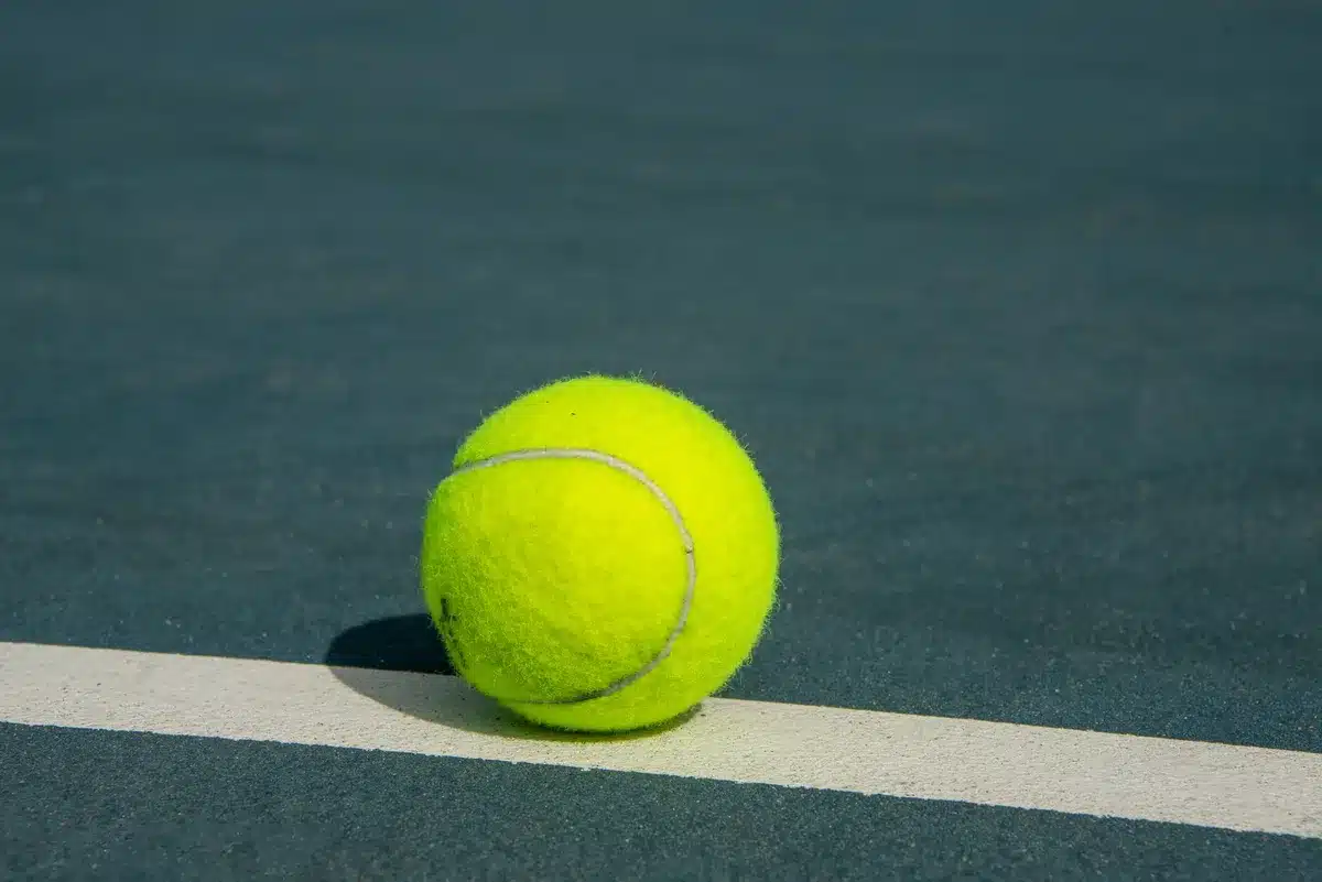 Två tennisspelare i intensiv rally på gräsmatta, en slår en kraftfull forehand medan motståndaren försvarar sig